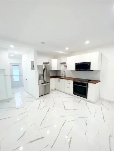 a large white kitchen with stainless steel appliances kitchen island granite countertop a stove top oven and a sink