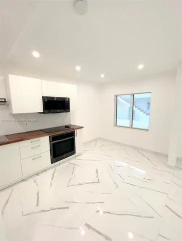 a kitchen with stainless steel appliances kitchen island granite countertop a sink a stove a microwave a counter top and cabinets