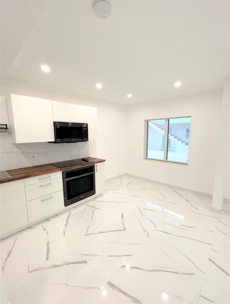 7300 Byron Avenue, Unit 10 Miami Beach, FL 33141 - Photo 5 of 10 a kitchen with stainless steel appliances kitchen island granite countertop a sink a stove a microwave a counter top and cabinets