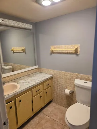a bathroom with a granite countertop toilet sink and mirror
