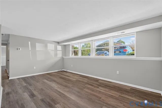 a view of an empty room with window and wooden floor