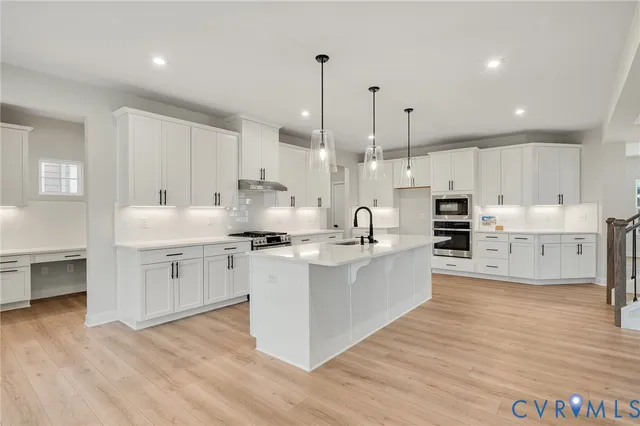 a kitchen with stainless steel appliances kitchen island granite countertop a wooden table chairs and white cabinets