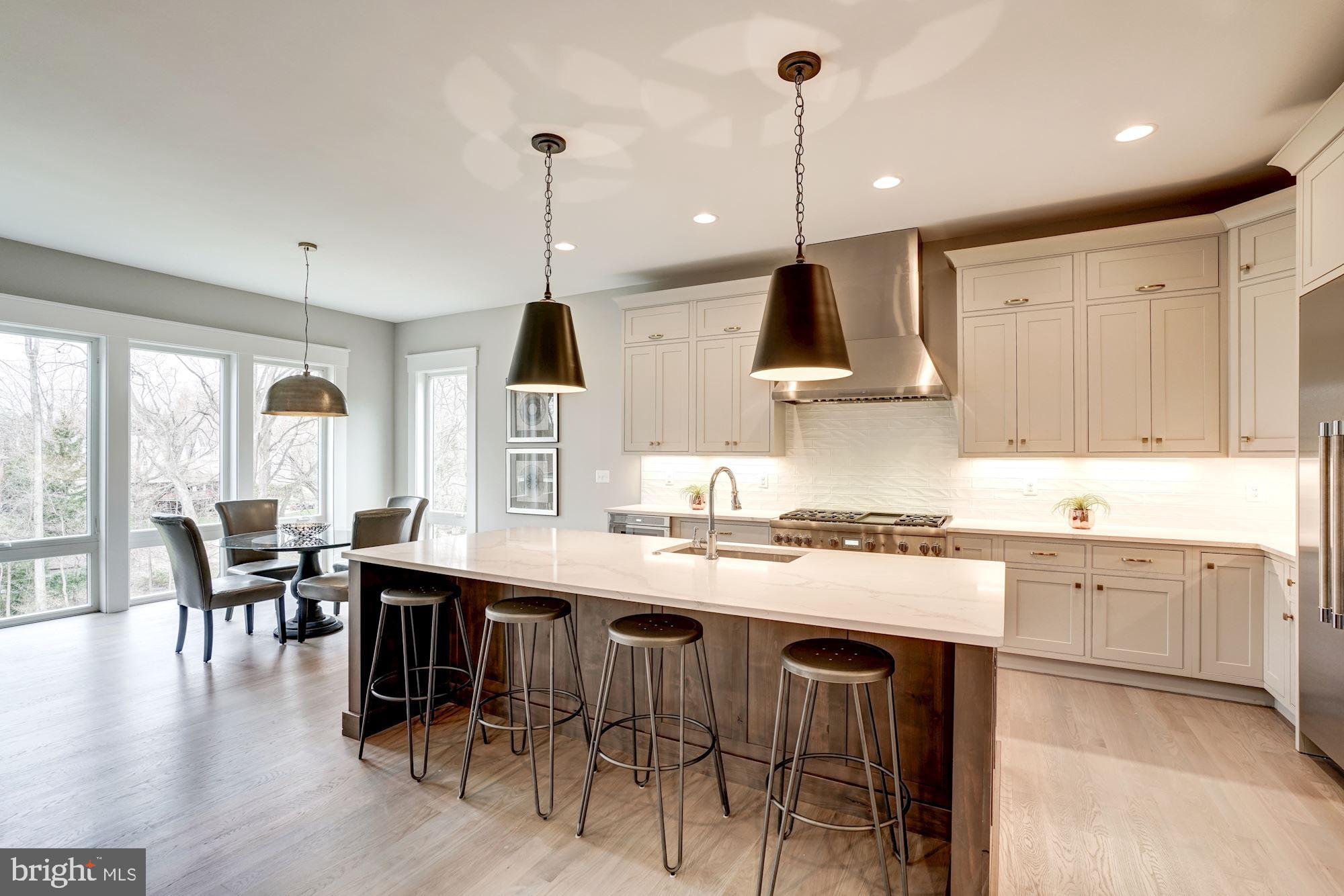 1826 Kirby Road McLean, VA 22101 - Photo 12 of 56 a kitchen with stainless steel appliances granite countertop a stove a refrigerator a kitchen island a dining table and chairs with wooden floor