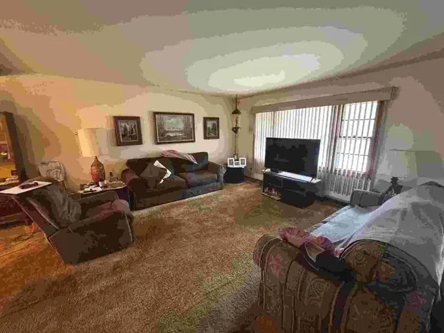 a living room with furniture a flat screen tv and a window