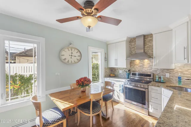 a kitchen with stainless steel appliances a stove a chandelier fan and a table