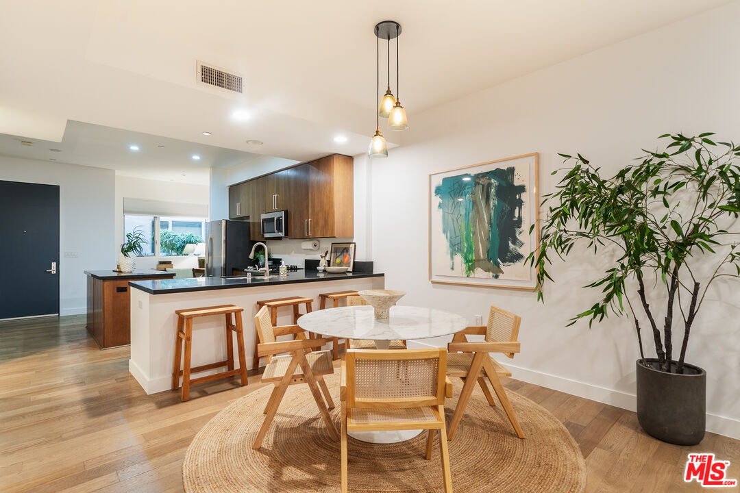 a kitchen with stainless steel appliances granite countertop a stove top oven a sink dishwasher and a dining table with wooden floor