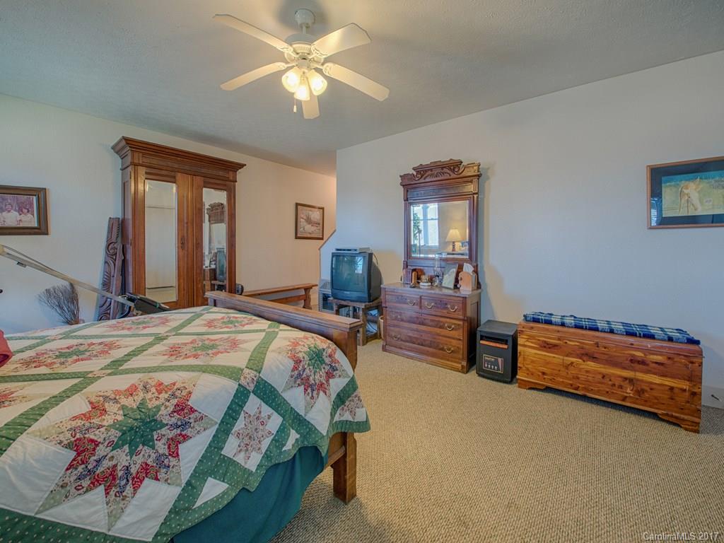 450 Windswept Ridge Road Leicester, NC 28748 - Photo 16 of 18 a bedroom with a bed and a chandelier