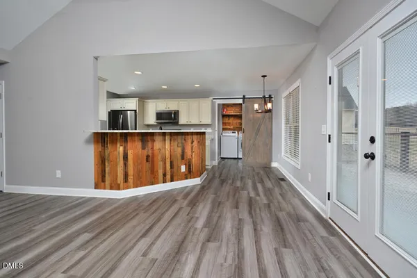 a kitchen with stainless steel appliances granite countertop a refrigerator a sink dishwasher a stove and white countertops with wooden floor