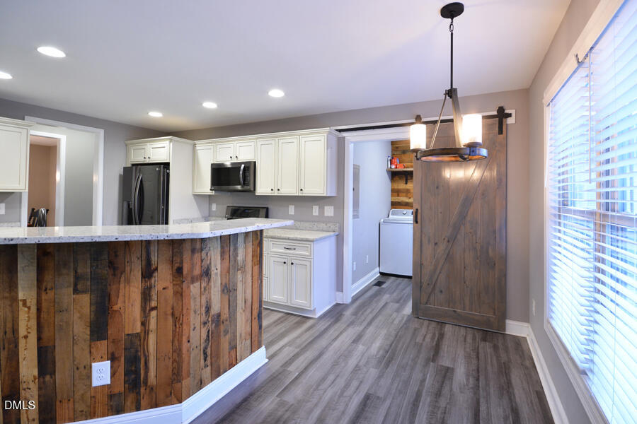 3082 East Thollie Green Road Stem, NC 27581 - Photo 12 of 45 a kitchen with stainless steel appliances granite countertop a refrigerator a sink dishwasher a stove and white countertops with wooden floor