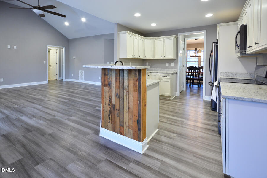 3082 East Thollie Green Road Stem, NC 27581 - Photo 13 of 45 a open kitchen with kitchen island a island wooden floors stainless steel appliances and cabinets