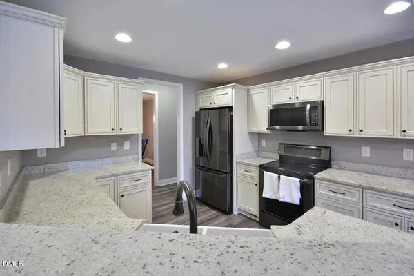 a kitchen with a sink dishwasher a stove and a refrigerator with wooden floor