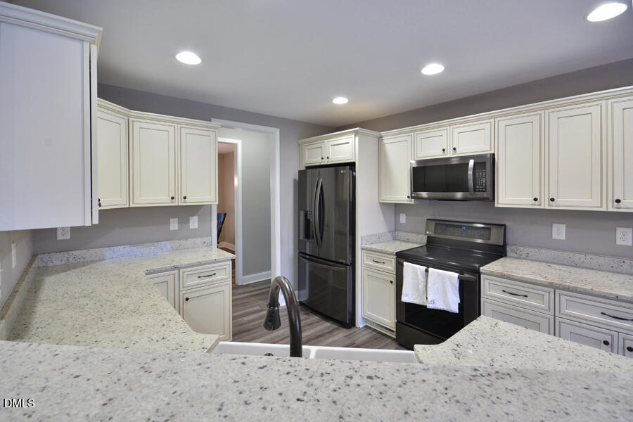 3082 East Thollie Green Road Stem, NC 27581 - Photo 14 of 45 a kitchen with granite countertop a refrigerator and a stove top oven