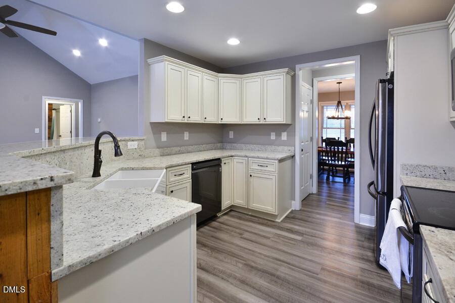 3082 East Thollie Green Road Stem, NC 27581 - Photo 15 of 45 a kitchen with a sink dishwasher a stove and a refrigerator with wooden floor