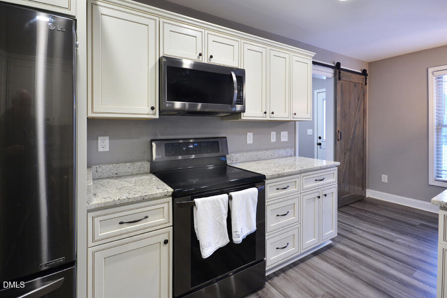 3082 East Thollie Green Road Stem, NC 27581 - Photo 18 of 45 a kitchen with stainless steel appliances granite countertop a stove a sink and a microwave