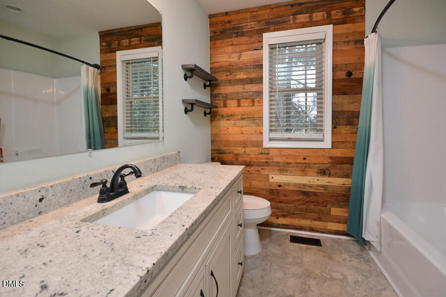 3082 East Thollie Green Road Stem, NC 27581 - Photo 33 of 45 a bathroom with a granite countertop sink a toilet and shower