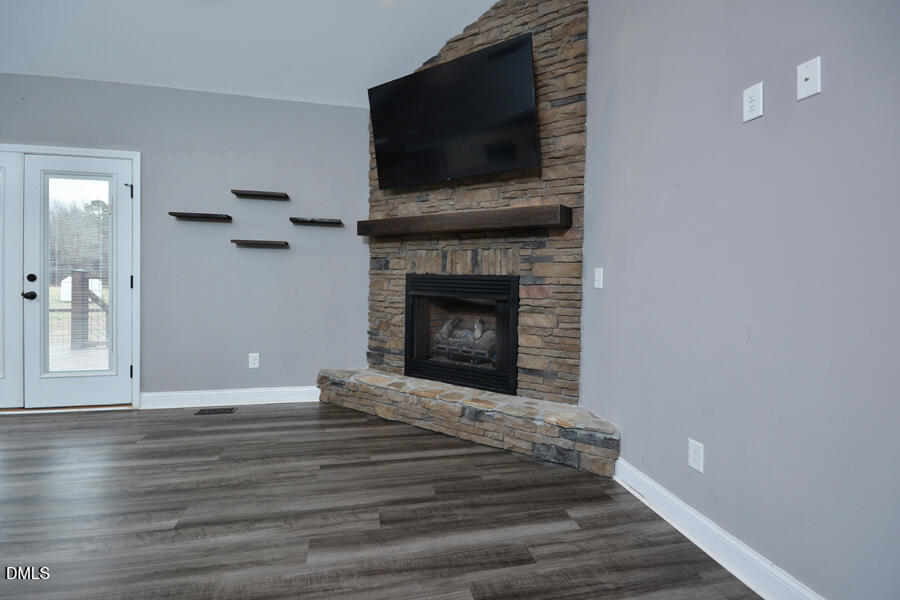 3082 East Thollie Green Road Stem, NC 27581 - Photo 9 of 45 a view of an empty room with wooden floor fireplace and a window