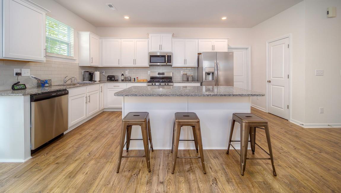 1240 Secrest Cmns Drive Monroe, NC 28112 - Photo 7 of 39 a kitchen with stainless steel appliances granite countertop white cabinets a sink a stove a dining table and chairs