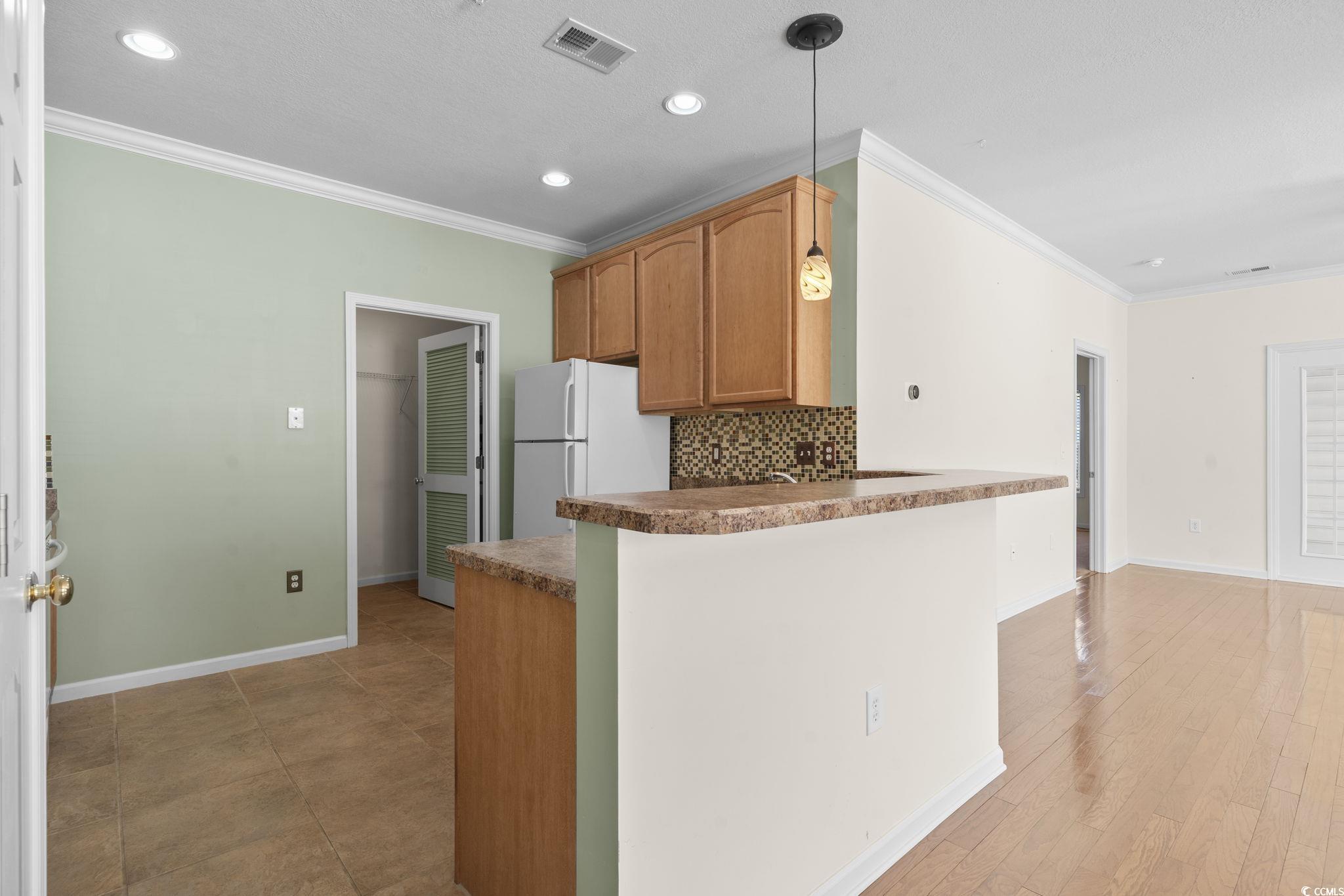 237 Moonglow Circle, Unit 102 Murrells Inlet, SC 29576 - Photo 8 of 35 Kitchen with ornamental molding, backsplash, freestanding refrigerator, recessed lighting, and hanging light fixtures