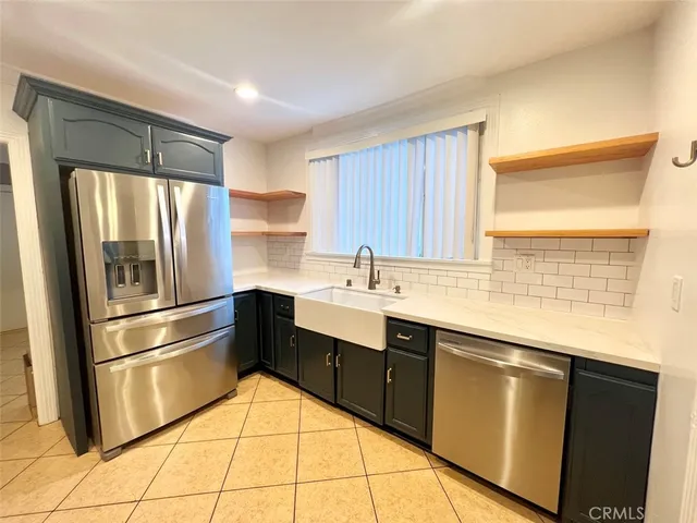 a kitchen with granite countertop stainless steel appliances a sink and a refrigerator