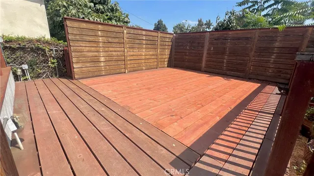 a view of deck with wooden floor and fence next to a yard