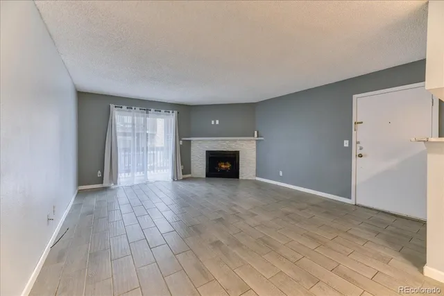 a view of an empty room with a fireplace and a window