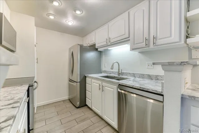 a kitchen with stainless steel appliances granite countertop a sink a stove a refrigerator and cabinets