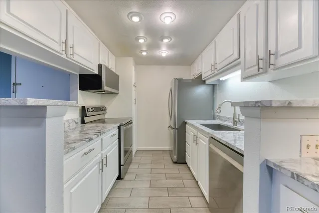 a kitchen with stainless steel appliances granite countertop a sink a stove top oven a refrigerator and dishwasher