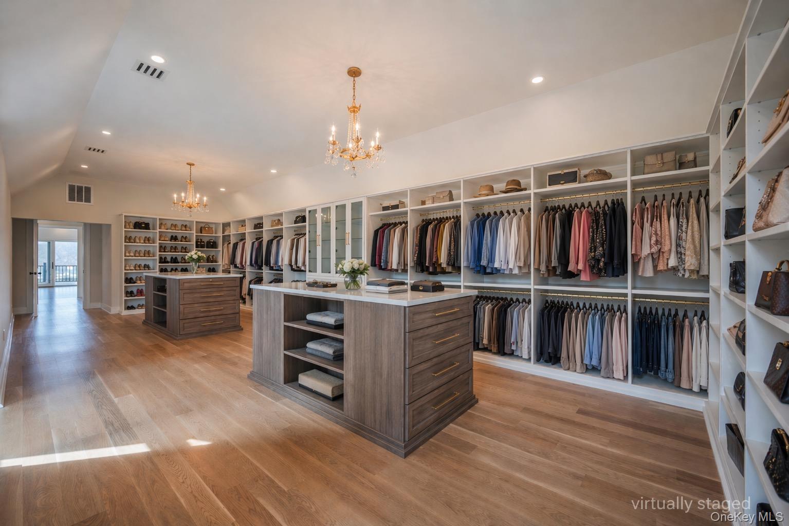 106 Cove Road Asharoken, NY 11768 - Photo 27 of 46 Spacious custom closet featuring light wood-finish flooring, two central islands with stone countertops, integrated shelving, and recessed lighting
