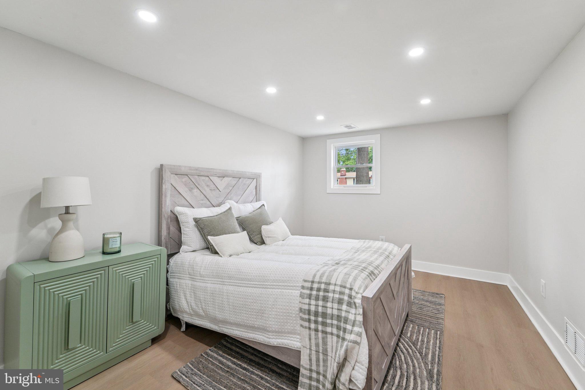 9168 Fort Smallwood Road Pasadena, MD 21122 - Photo 13 of 42 a bedroom with a bed and a lamp with the wooden floor