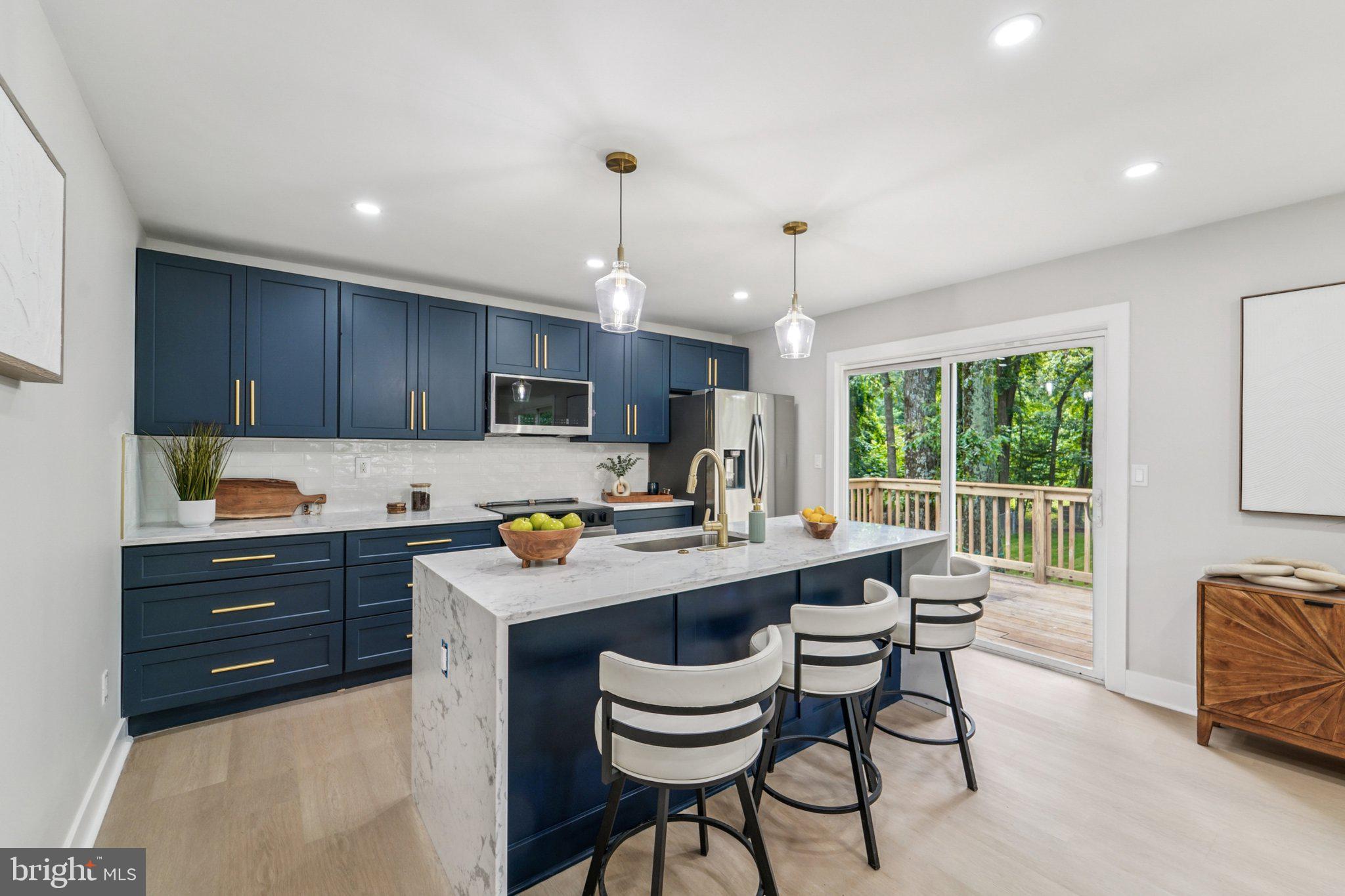 9168 Fort Smallwood Road Pasadena, MD 21122 - Photo 3 of 42 a kitchen with stainless steel appliances granite countertop a stove top oven a sink dishwasher a dining table and chairs with wooden floor