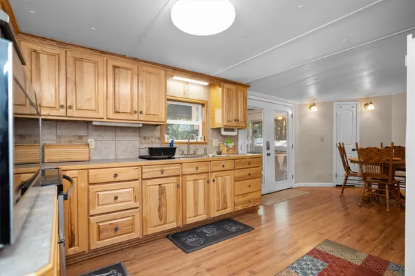 a kitchen with stainless steel appliances granite countertop a stove a sink dishwasher and a refrigerator with wooden floor