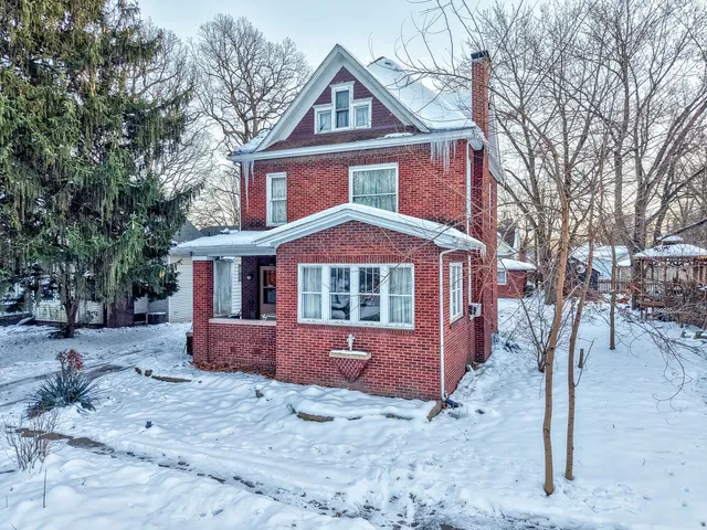 a front view of a house with a yard covered in snow