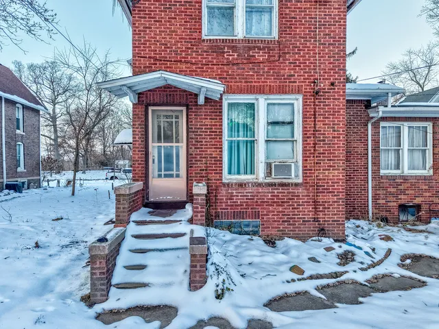 a front view of a house with a yard covered with snow
