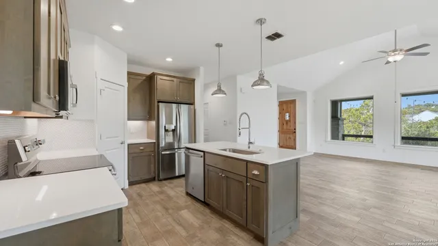 a kitchen with a stove a sink a window and wooden floor