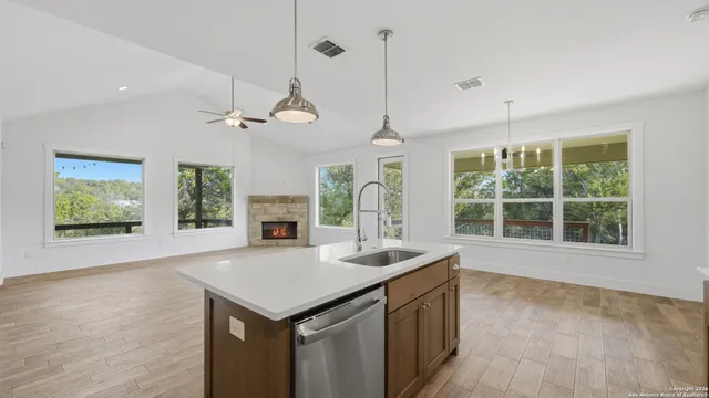 a large kitchen with a refrigerator a sink dishwasher a oven and a dining table with wooden floor