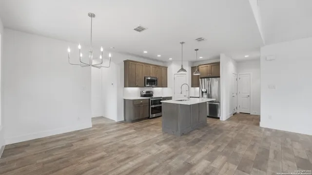 a view of an empty room with window and chandelier fan