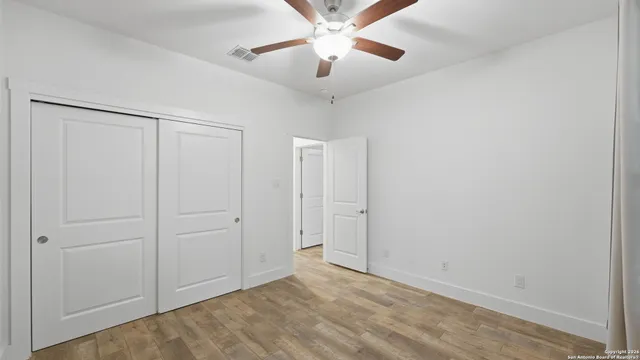 an empty room with windows and a ceiling fan