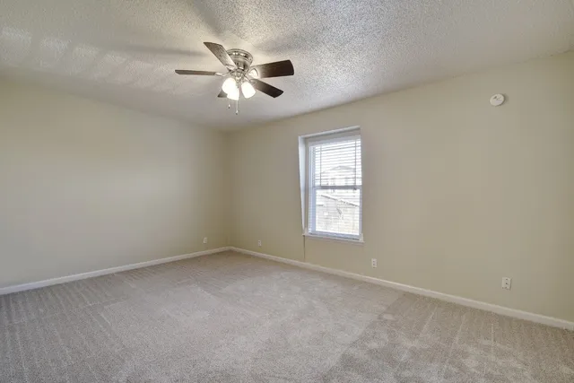 an empty room with windows and fan
