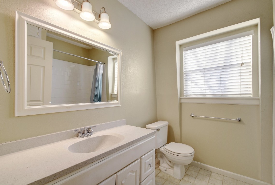 1704 East M. Franklin Avenue, Unit C Austin, TX 78721 - Photo 12 of 18 a bathroom with a granite countertop toilet a sink a mirror and a window