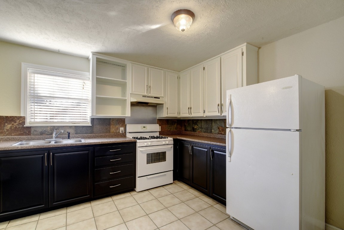 1704 East M. Franklin Avenue, Unit C Austin, TX 78721 - Photo 6 of 18 a kitchen with stainless steel appliances granite countertop white refrigerator stove a sink and dishwasher with a refrigerator