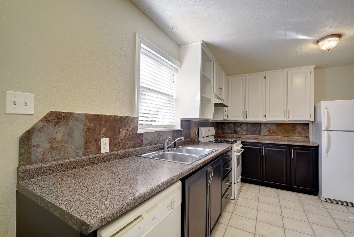 1704 East M. Franklin Avenue, Unit C Austin, TX 78721 - Photo 8 of 18 a kitchen with a sink dishwasher a stove and a refrigerator with wooden cabinets