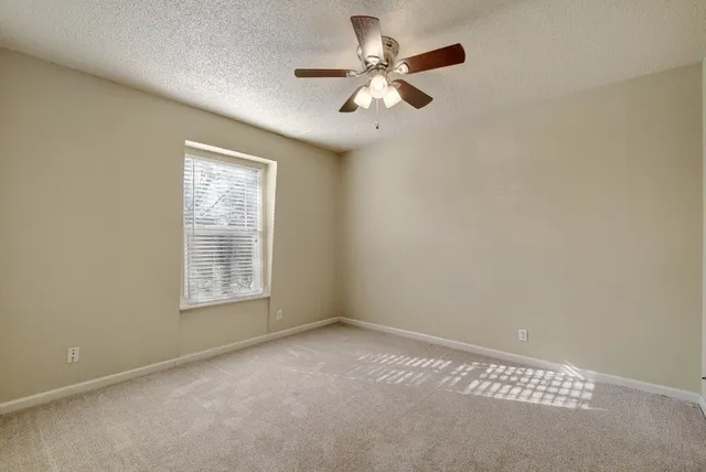 an empty room with windows and fan