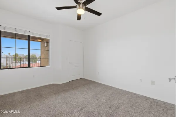 an empty room with a window and ceiling fan
