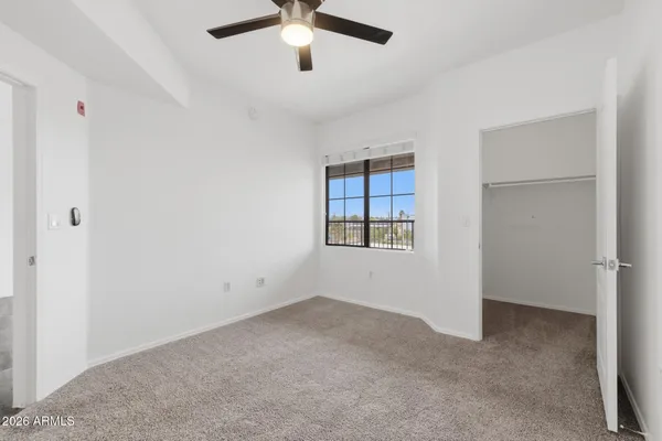 an empty room with ceiling fan and window