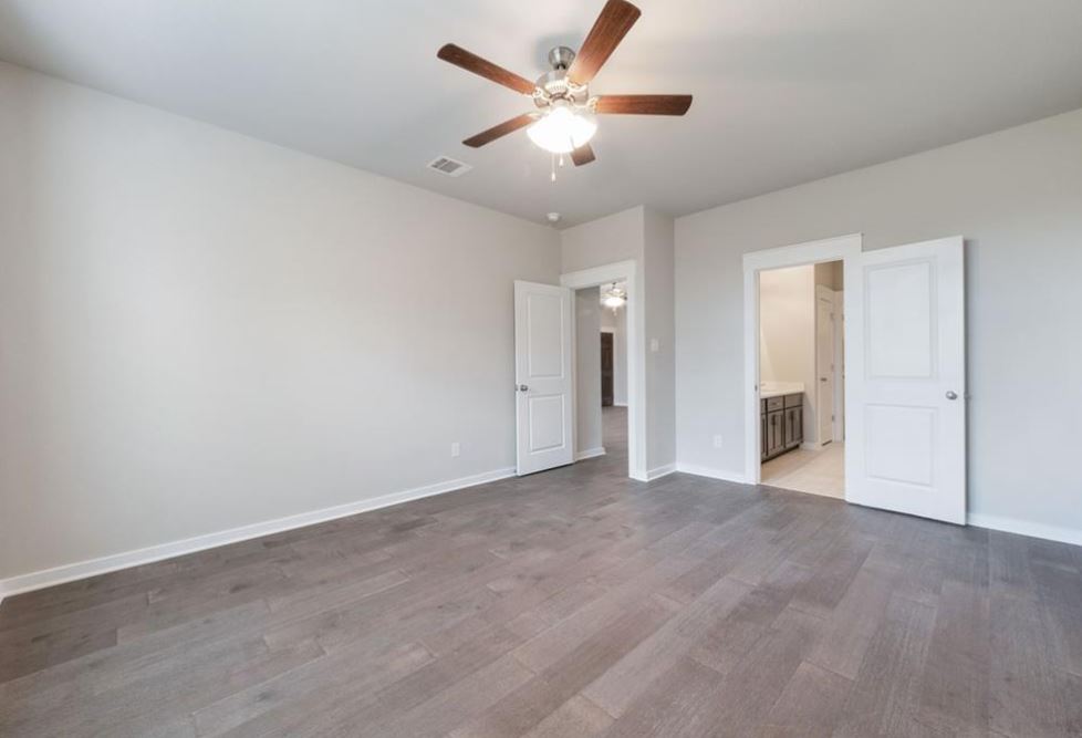 2221 Rocoso Trail Leander, TX 78641 - Photo 7 of 16 Unfurnished bedroom featuring a ceiling fan, ensuite bath, and wood finished floors