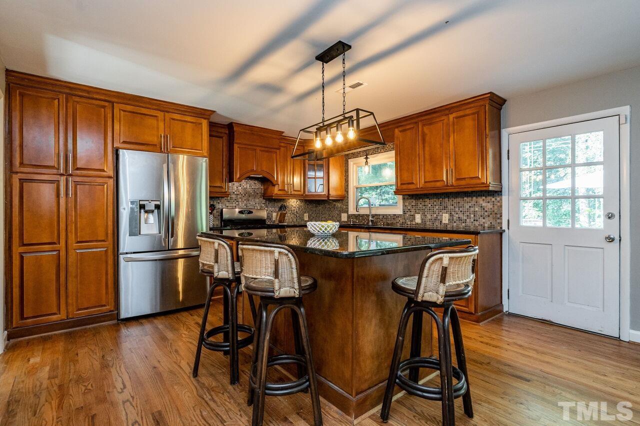 1500 Windbur Place Raleigh, NC 27609 - Photo 7 of 30 a kitchen with granite countertop wooden floors and stainless steel appliances