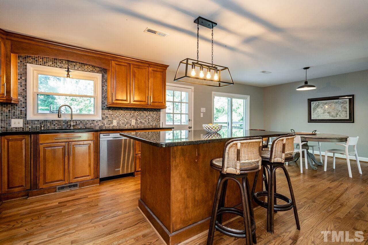 1500 Windbur Place Raleigh, NC 27609 - Photo 9 of 30 a kitchen with stainless steel appliances granite countertop wooden floors a stove a microwave a dining table and chairs