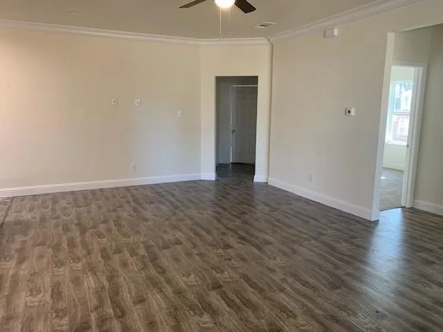 wooden floor in an empty room with a chandelier fan