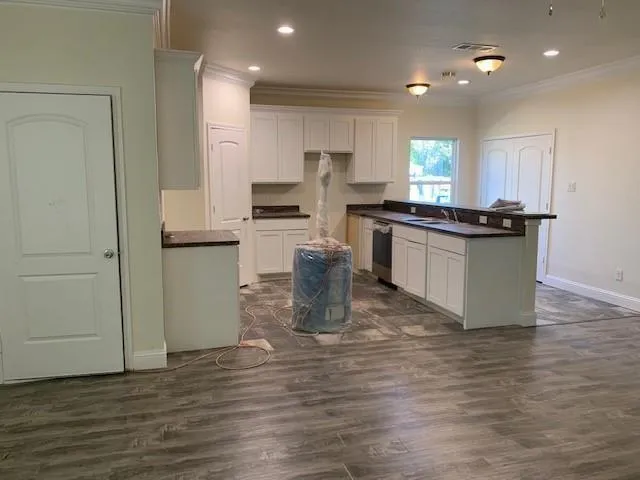 a kitchen with kitchen island granite countertop a stove and a wooden floors