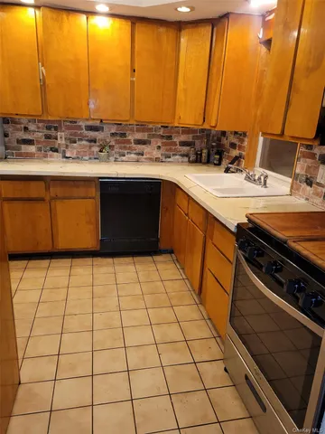 a kitchen with a sink a stove top oven and a view of living room